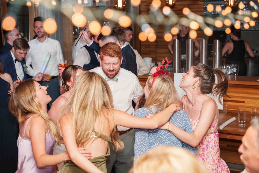 Fröhliche Menschen feiern ausgelassen bei einer Party, tanzen und lachen unter festlicher Beleuchtun.