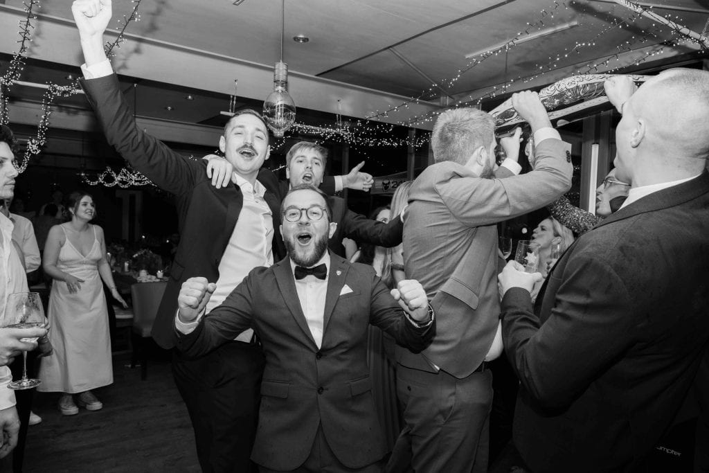 Hochzeitsparty mit lachenden Gästen, die ausgelassen feiern und tanzen.