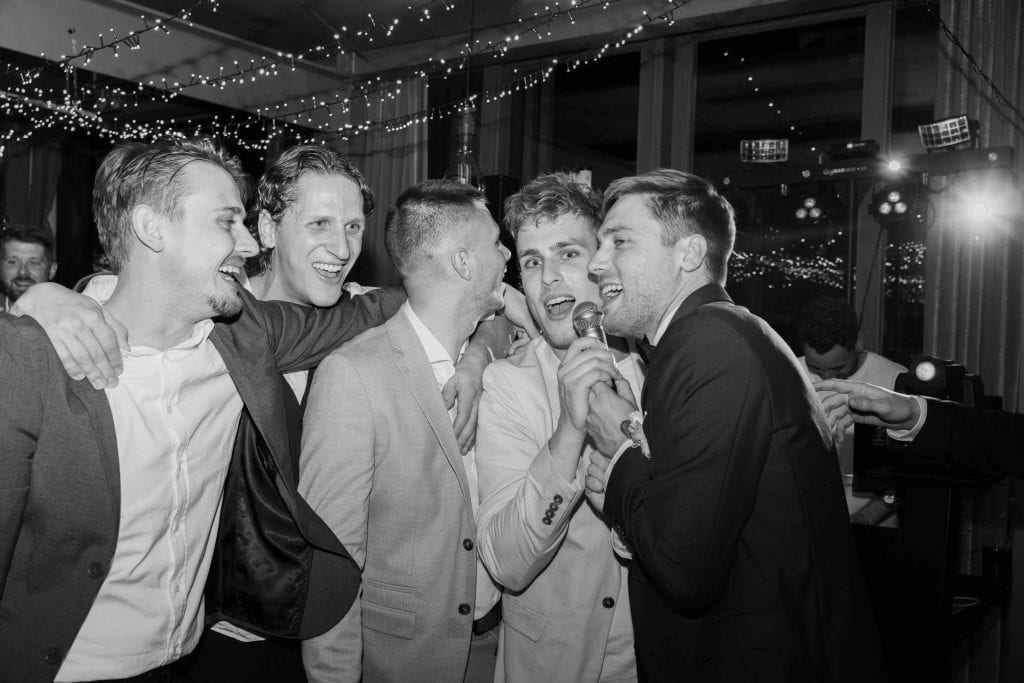Feiernde Freunde bei einer Hochzeit, lachen und tanzen zusammen in festlicher Atmosphäre.