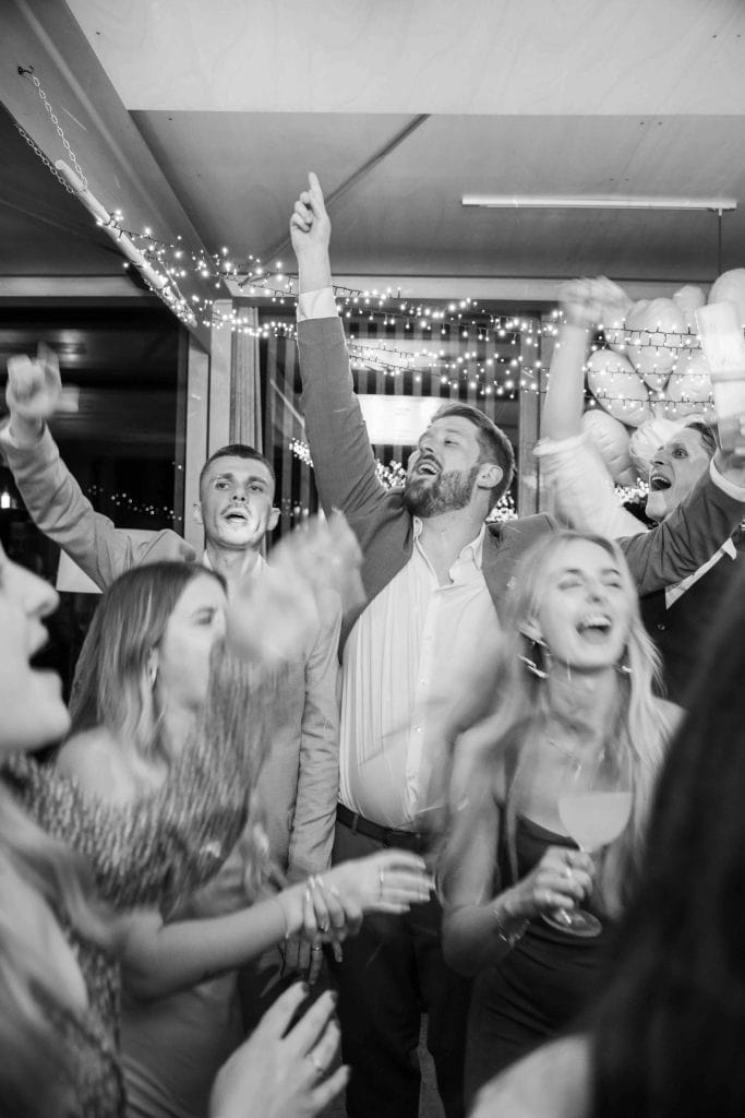 Feiernde Menschen bei Party, lachen und tanzen unter Lichterketten, festliche Stimmung, Spaß und Fre.