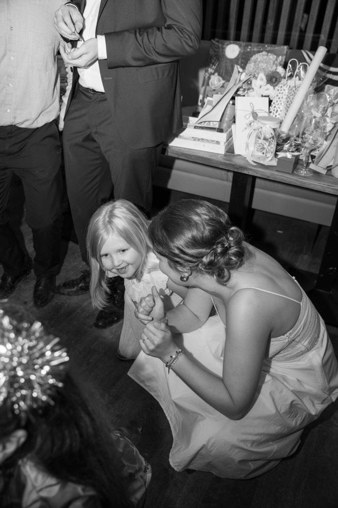 Frau übergibt Geschenk an Kind bei Feier, festliche Atmosphäre, Weihnachtsdekoration.