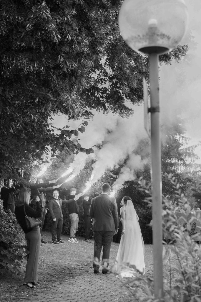 Hochzeit im Freien bei Nacht mit Brautpaar und Gästen, romantische Atmosphäre, umgeben von Bäumen un.