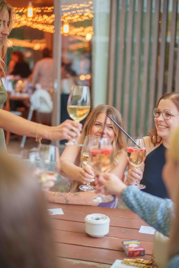 Freunde beim Wein trinken im Garten, lachen und genießen den Abend.