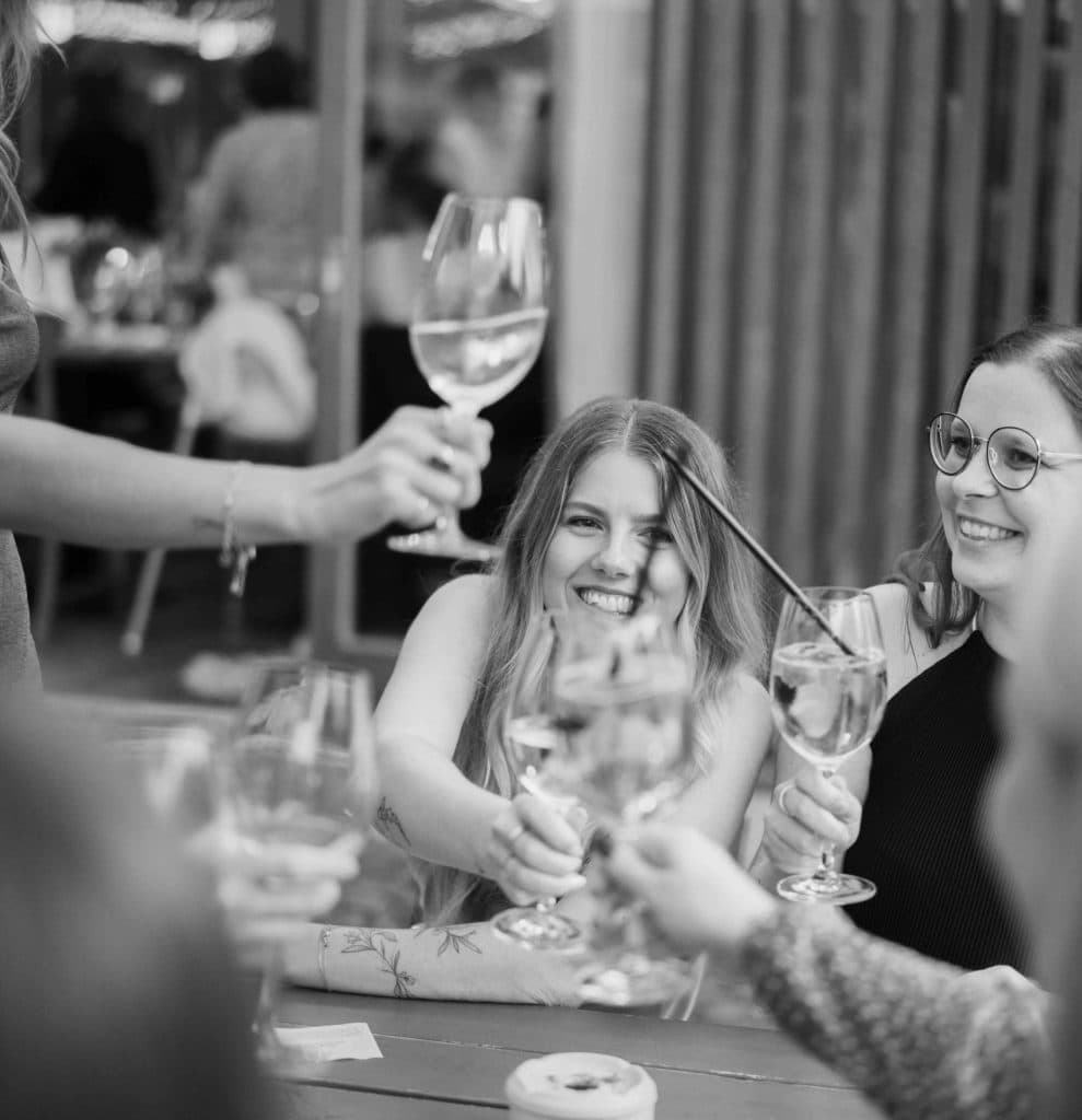 Freunde beim Wein trinken, lachen und feiern bei einem geselligen Treffen im Garten.