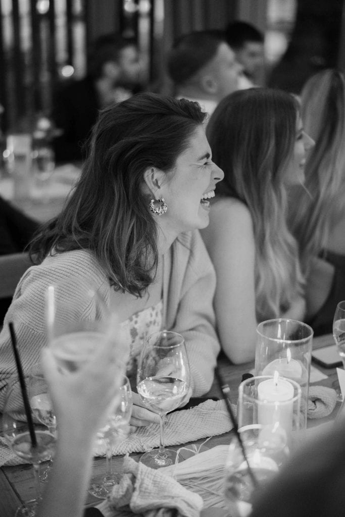 Frauen lachen und genießen ein gemeinsames Abendessen bei einer Feier.
