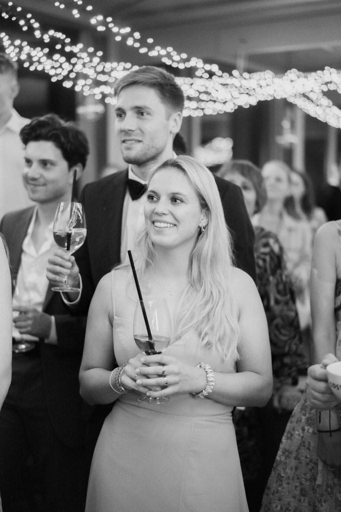 Hochzeitspaar bei festlicher Feier mit Freunden, stilvolle Dekoration im Hintergrund.