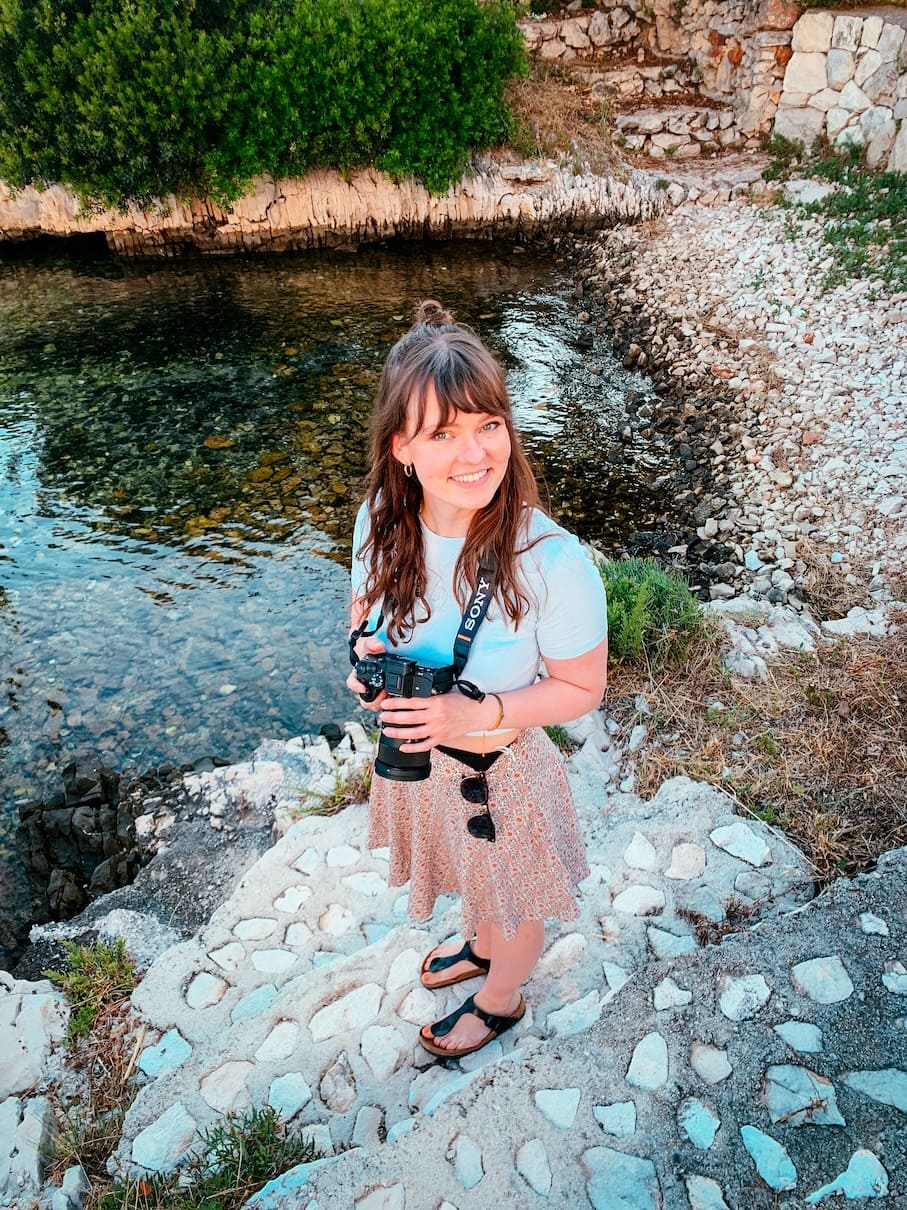 Frau mit Kamera am Flussufer, Naturaufnahme, Outdoor-Fotografie.
