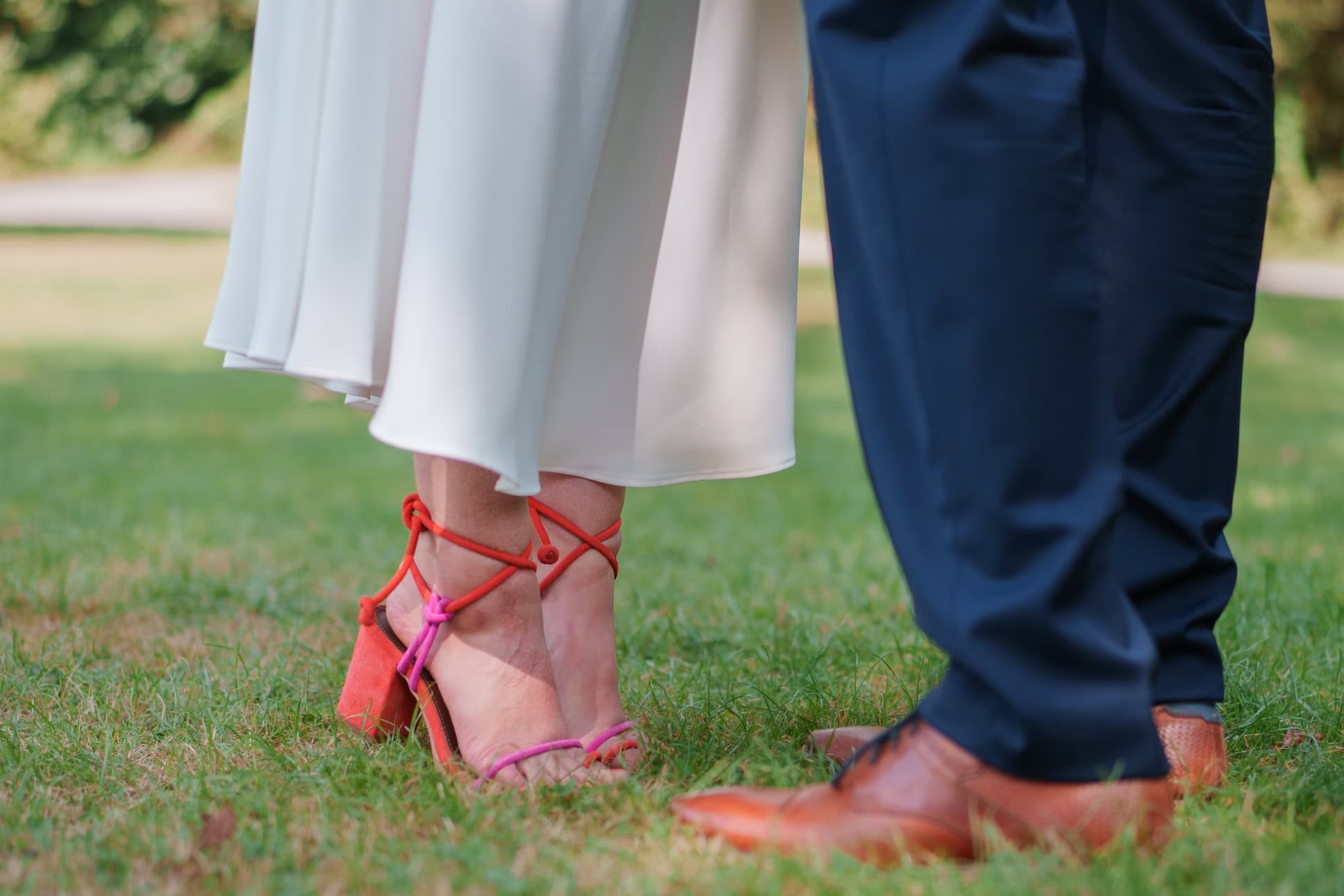 Hochzeitspaar mit Fokus auf Schuhe und Kleidung im Freien.